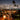Evening view of the clear 16" LA Pipes 16" Clear UFO Showerhead Perc Beaker Bong on a balcony table with city lights and palm trees blurred behind.