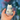A hand holds the white Donut Bear Pipe, viewed from the side against a blurred blue background.