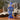Close-up front view of the blue MAV Glass The Humboldt Recycler on a wooden table with an open book and a blurred couch background.