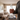 Close-up of a person holding the clear LA Pipes 8" Bubble Beaker Bong by its straight neck against a softly lit living room background