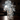 Three-quarter view of the LA Pipes Mini Bubble Beaker Rig with swirling smoke rising against a dim, book-lined background